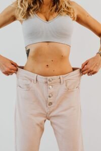 A woman showcases her weight loss journey by wearing loose-fitting trousers.